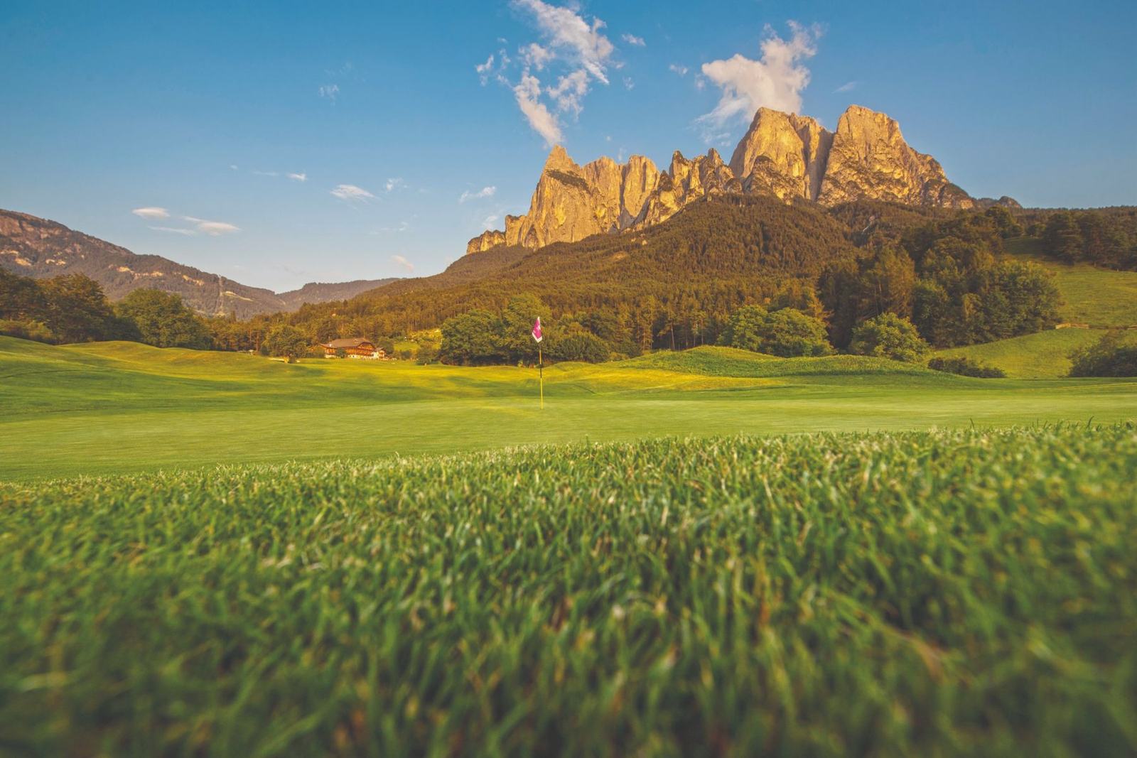 Golfplatz St. Vigil Seis mit dem Feldererhof am Waldrand und dem Schlern im Abendlicht