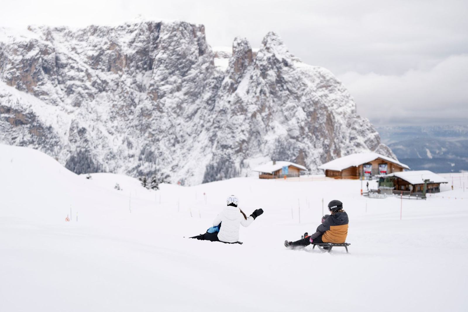 Rodler im Schnee vor den Dolomiten